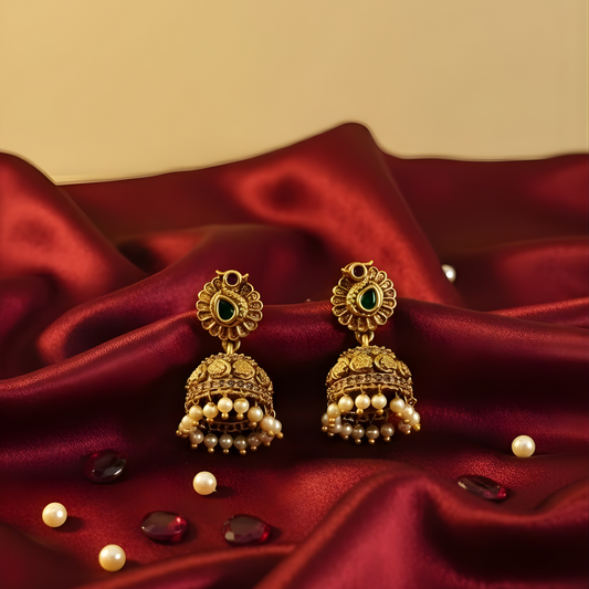 Antique gold earrings with green stones and pearl drops on beige background