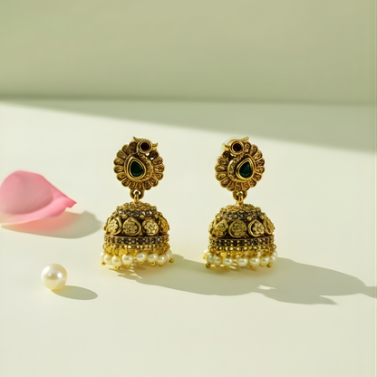 Antique gold earrings with green stones and pearl drops on beige background