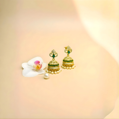 Gold and green jhumka earrings with pearl drops on beige background